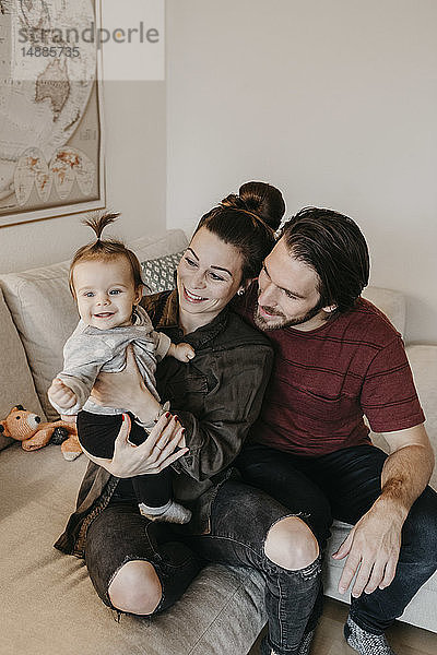 Glückliche Familie mit Mädchen zu Hause im Wohnzimmer