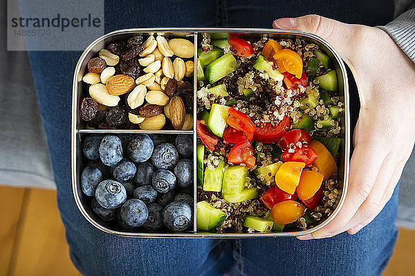 Mädchen hält eine Lunchbox mit Quinoa-Salat  Blaubeeren und Studentenfutter