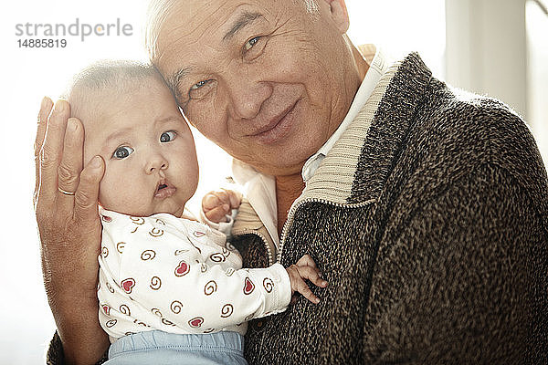 Porträt eines glücklichen Grossvaters Kopf an Kopf mit seiner Enkelin