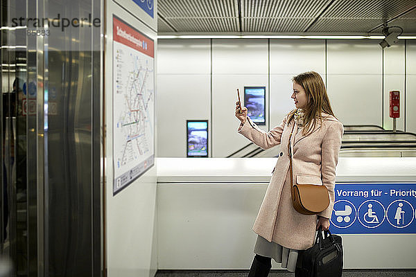 Österreich  Wien  junge Frau beim Fotografieren der Karte in der U-Bahn-Station