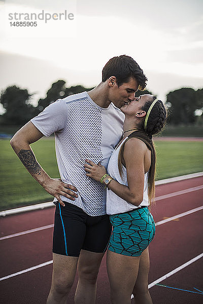 Männlicher und weiblicher Athlet küssen sich auf der Tartanbahn