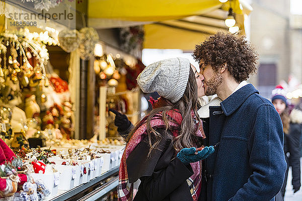 Glückliches  liebevolles  junges Paar küsst sich auf dem Weihnachtsmarkt