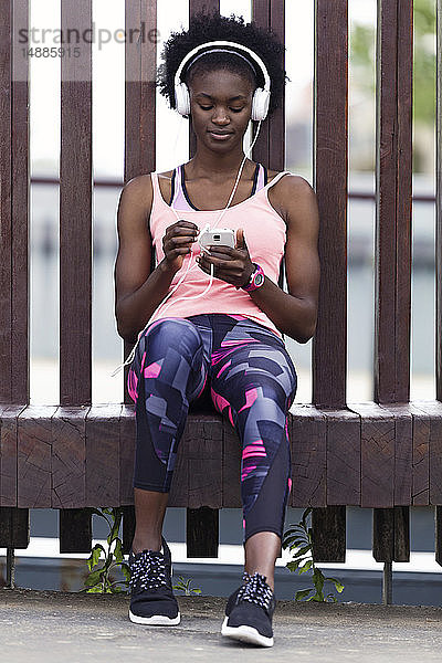 Sportliche junge Frauen entspannen sich mit Kopfhörern und Mobiltelefonen