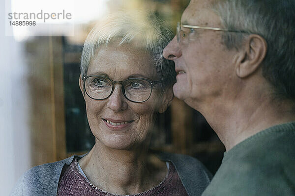 Zuversichtliches älteres Ehepaar schaut aus dem Fenster
