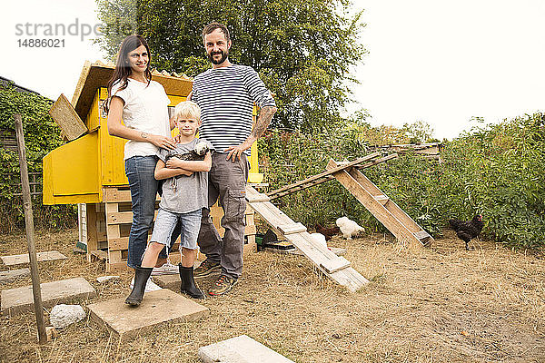 Porträt einer selbstbewussten Familie mit polnischem Huhn im Hühnerstall im Garten
