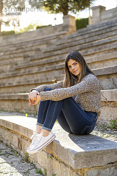Porträt einer jungen Frau  die auf einer Treppe im Freien sitzt