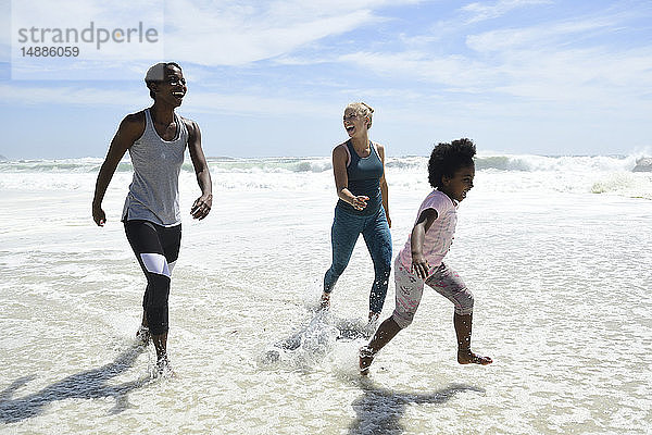 Mutter mit Tochter und Freundin haben Spaß beim Surfen am Strand