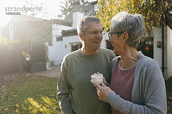 Glückliches älteres Ehepaar mit einer Tasse Kaffee im Garten