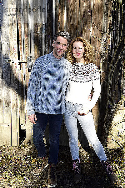 Lächelndes Paar steht vor Holzhütte