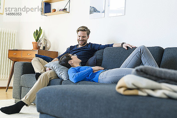 Glückliches Paar entspannt sich auf einer Couch in seinem modernen Wohnzimmer