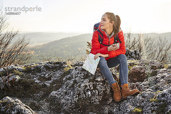 Frau auf Bergwanderung in den Bergen auf einem Felsen sitzend bei einer Pause