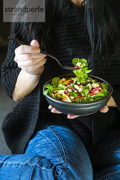 Frau isst gemischten Salat mit Feldsalat  Feta  Birne  Granatapfelkernen und Walnüssen