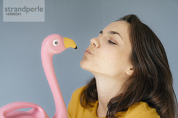 Frau küsst rosa Flamingo-Figur