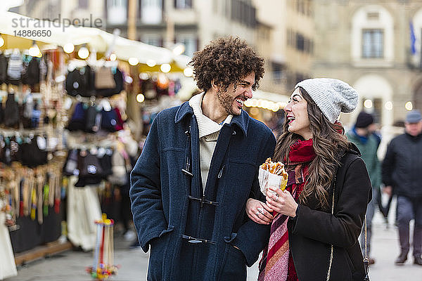 Glückliches junges Paar schlendert auf dem Weihnachtsmarkt
