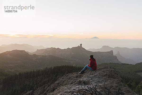 Spanien  Gran Canaria  Pico de las Nieves  Frau sitzt auf einem Felsen und schaut auf die Aussicht