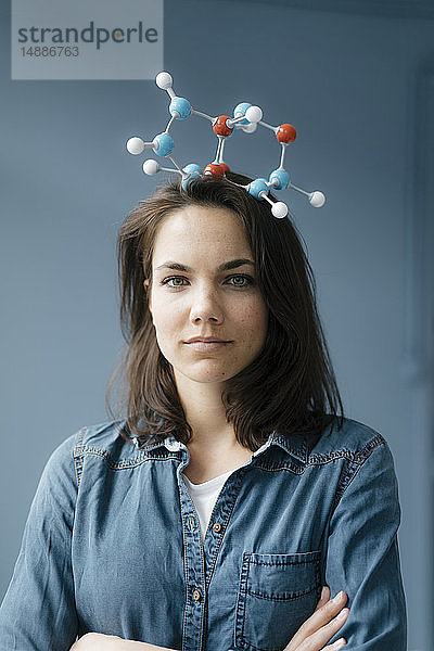 Weibliche Wissenschaftlerin balanciert Molekülmodell auf ihrem Kopf