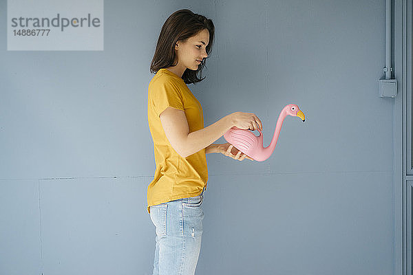 Frau hält rosa Flamingo-Giesskanne