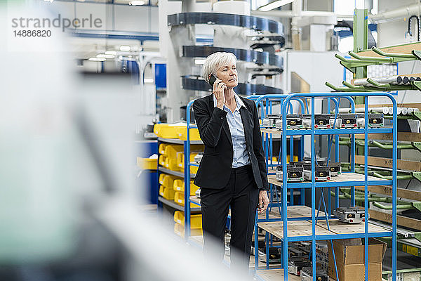 Leitende Geschäftsfrau am Handy in einer Fabrik