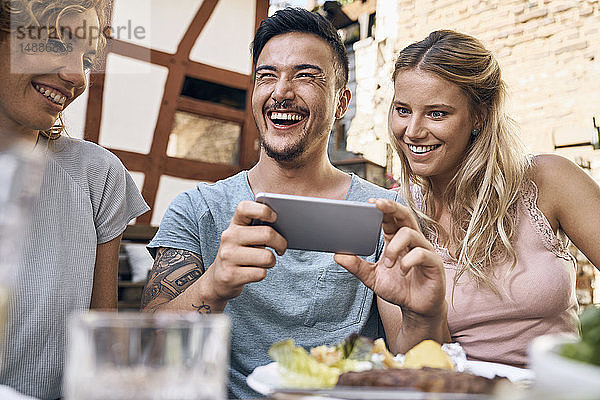 Freunde amüsieren sich auf einer Grillparty und fotografieren mit ihren Smartphones