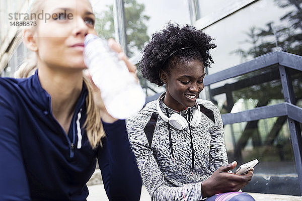 Zwei sportliche junge Frauen entspannen sich nach dem Laufen in der Stadt