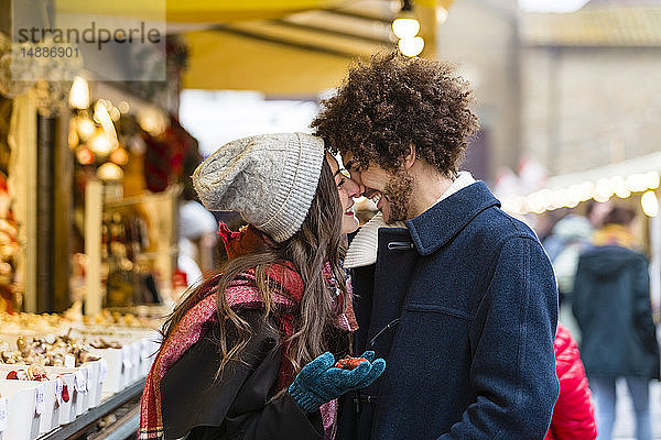 Glückliches  liebevolles junges Paar auf dem Weihnachtsmarkt