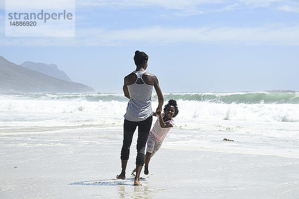 Glückliche Mutter und Tochter amüsieren sich am Strand
