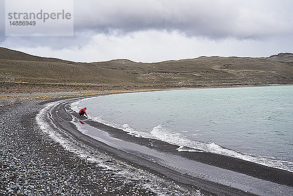 Chile  Patagonien  Mann berührt kaltes Wasser im Torres del Paine Nationalpark