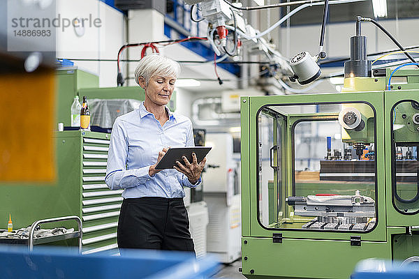 Leitende Geschäftsfrau mit Tabletten in einer Fabrik