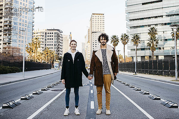 Porträt eines Paares  das sich mitten auf der Strasse an den Händen hält