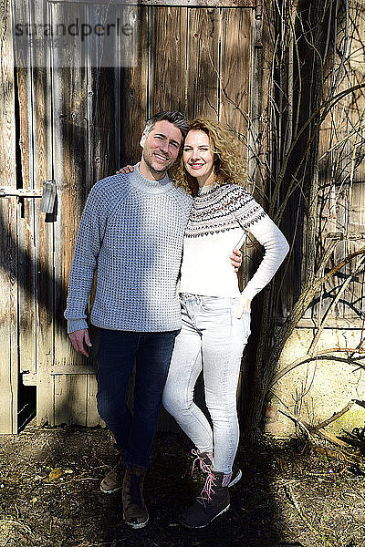 Lächelndes Paar steht vor Holzhütte