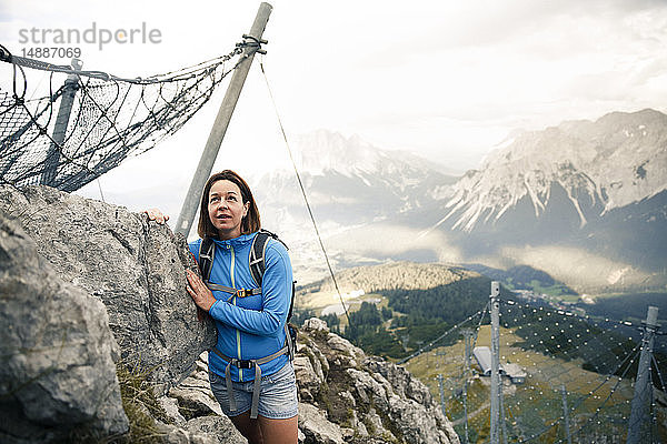 Österreich  Tirol  Frau auf einer Wanderung in den Bergen am Fels stehend