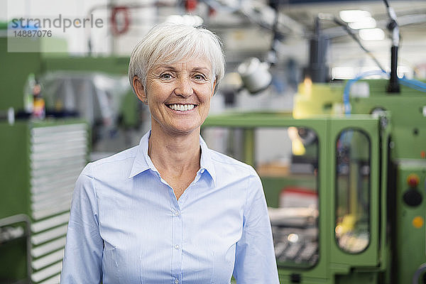 Porträt einer lächelnden älteren Geschäftsfrau in einer Fabrik