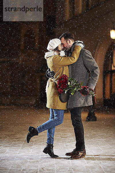 Verliebtes Paar umarmt sich im Winter in der Stadt