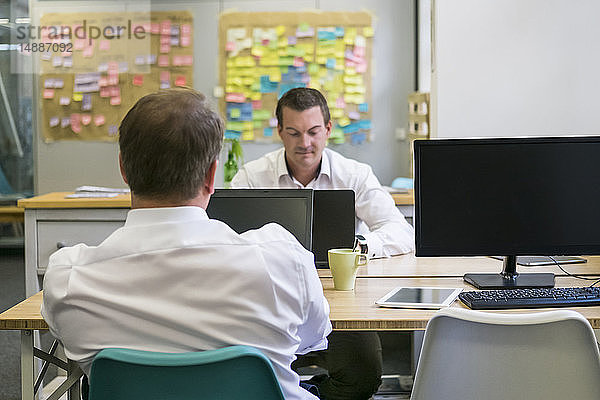 Zwei Geschäftsleute arbeiten am Schreibtisch im Büro