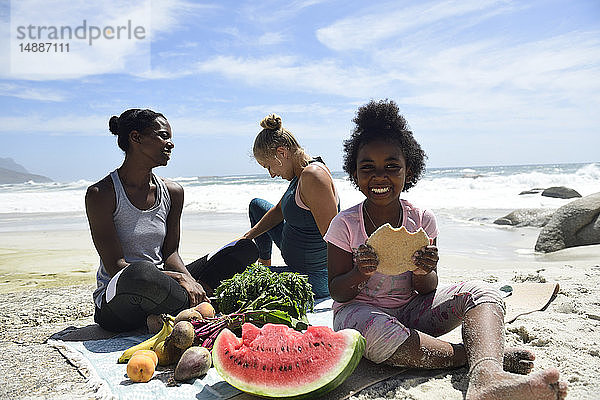 Mutter mit Tochter und Freundin beim Picknick am Strand