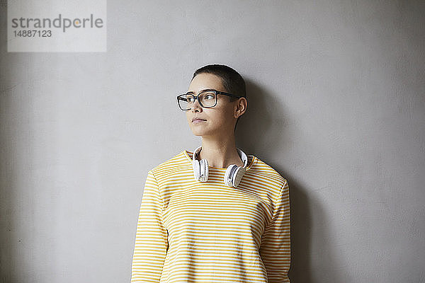 Porträt einer kurzhaarigen jungen Frau mit Brille und Kopfhörer