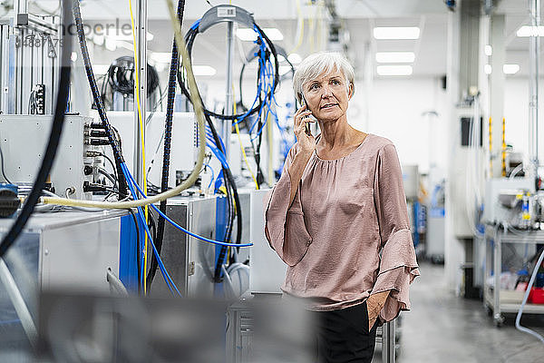 Ältere Frau am Handy in einer Fabrik