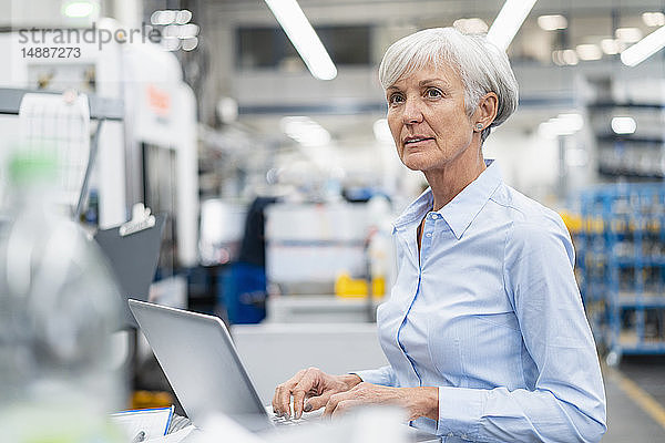 Leitende Geschäftsfrau mit Laptop in einer Fabrik