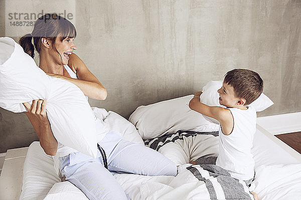 Mutter und Sohn amüsieren sich  machen eine Kissenschlacht im Bett