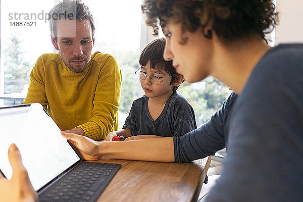 Familie am Tisch sitzend  mit digitalem Tablett