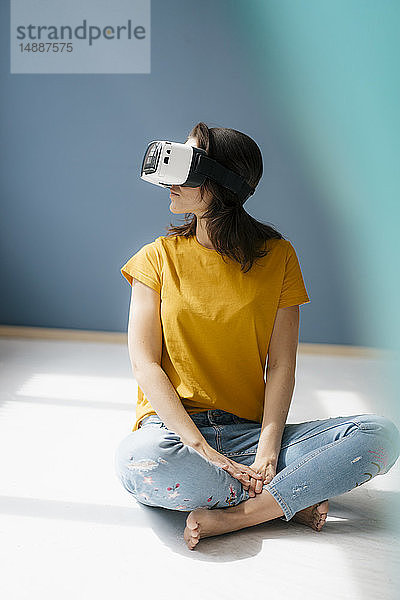 Frau sitzt im Schneidersitz auf dem Boden und trägt eine VR-Brille