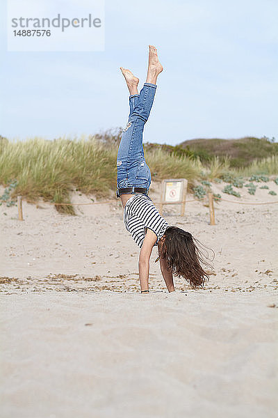 Spanien  Menorca  barfüßige junge Frau beim Handstand am Strand