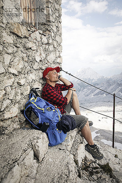 Österreich  Tirol  Mann auf Wanderung  der sich mit geschlossenen Augen auf einer Berghütte ausruht