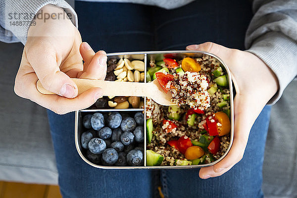 Lunchbox mit Quinoa-Salat mit Tomate und Gurke  blauen Beeren und Studentenfutter