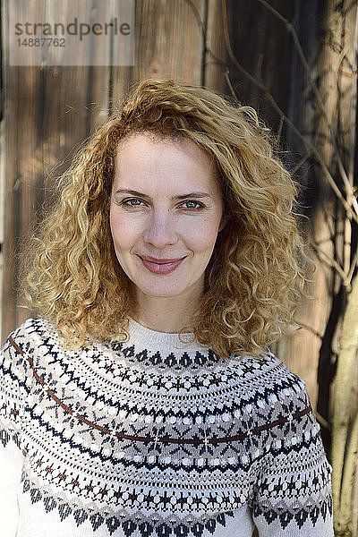 Blonde Frau mit lockigem Haar lächelt  norwegischer Pullover