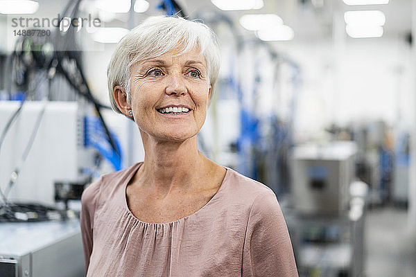 Porträt einer lächelnden älteren Frau in einer Fabrik