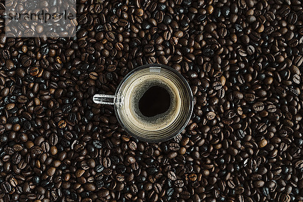 Glas schwarzer Kaffee zwischen Kaffeebohnen