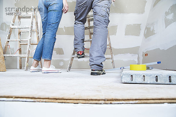 Beine eines Paares mit Leiter im Dachgeschoss  das renoviert werden soll