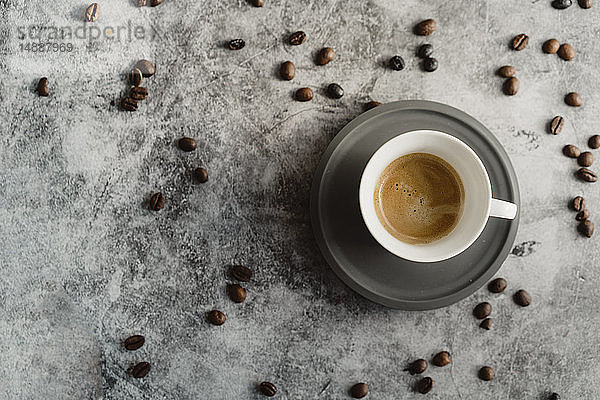 Tasse Espresso und verstreute Kaffeebohnen
