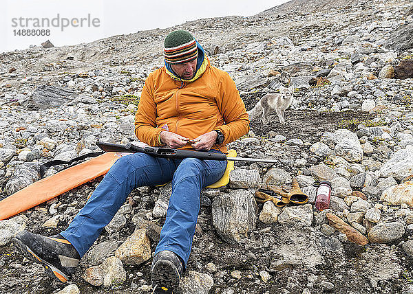 Grönland  Sermersooq  Kulusuk  Schweizer Alpen  Mann mit Gewehr und Polarfuchs